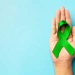 world mental health day green ribbon put in human s hand on blue background min