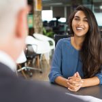 mulher sorrindo em entrevista de emprego para ilustrar texto sobre salário