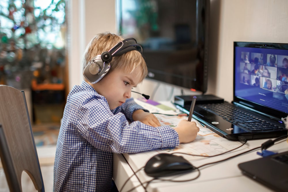 criança estudando no computador para ilustrar texto sobre ensino híbrido