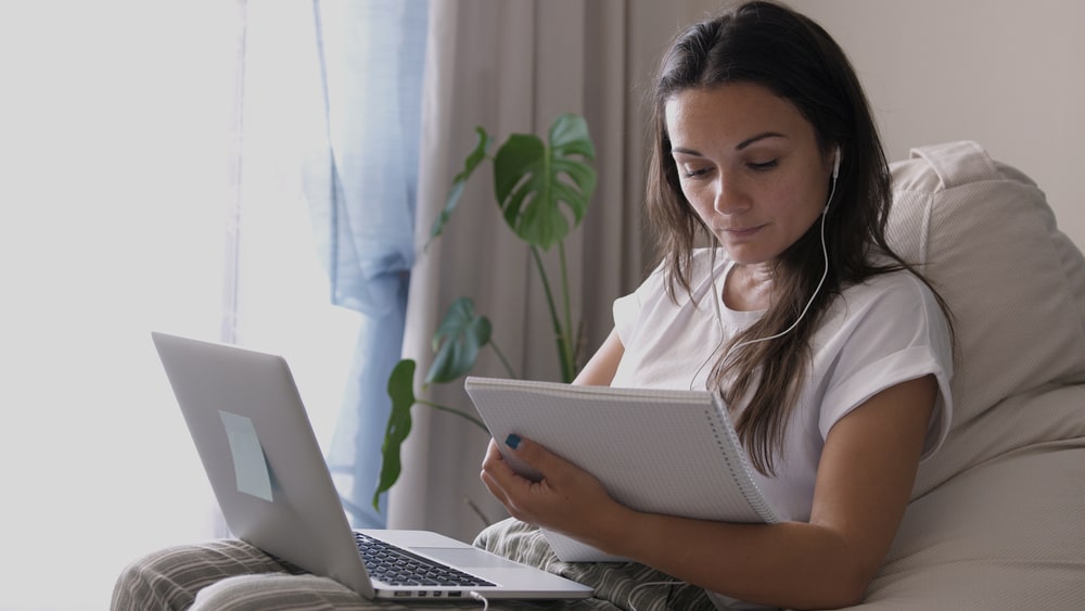 mulher com notebook e folhas na mão para ilustrar conteúdo sobre qualidade da pós-graduação