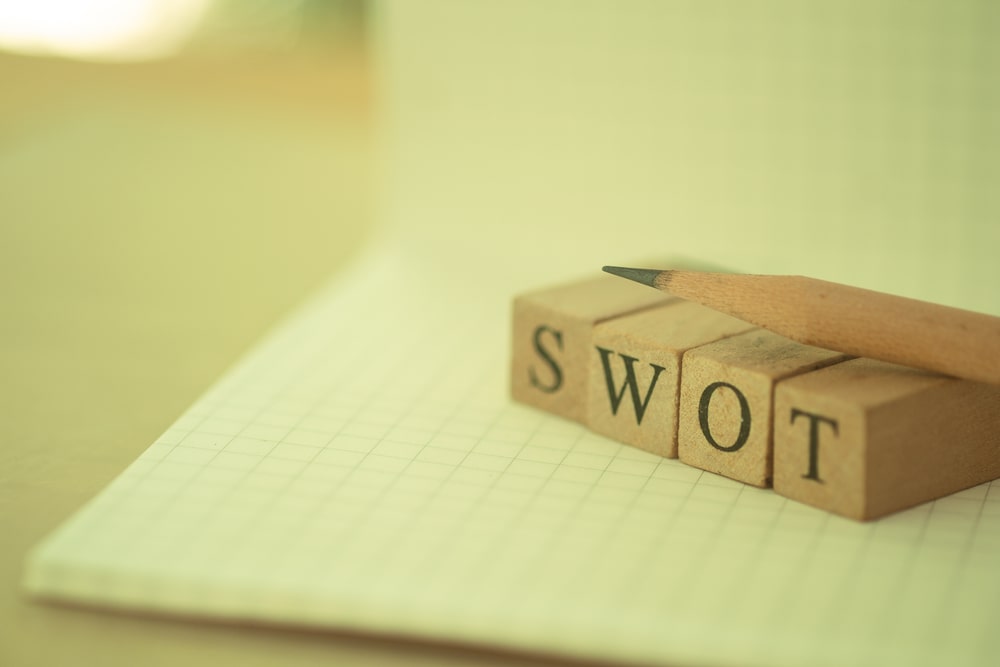 imagem com caderno, lápis e a escrita SWOT para ilustrar texto sobre matriz SWOT