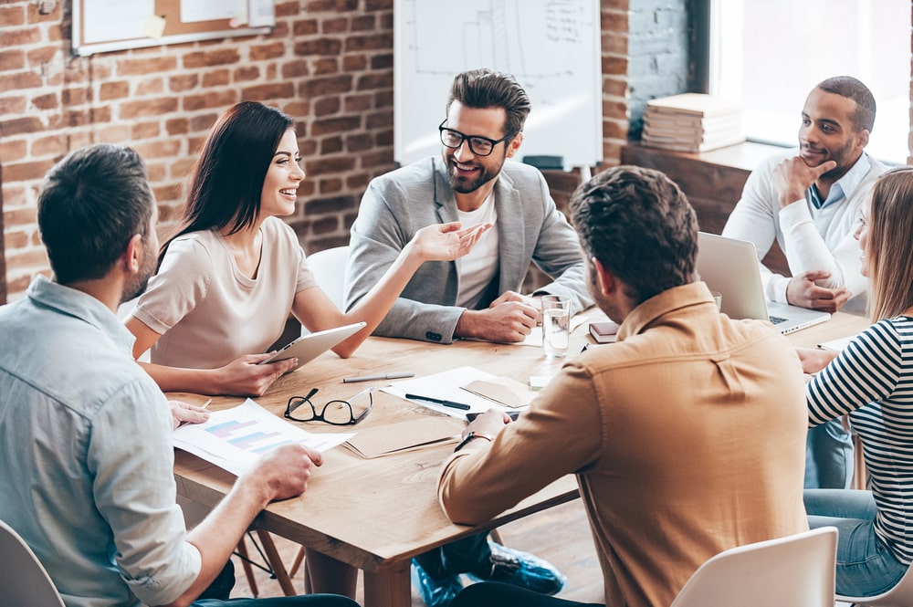 equipe reunida em uma mesa no escritório para ilustrar conteúdo sobre como se adaptar ao novo emprego