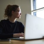 mulher com notebook pensativa para representar texto sobre como se manter atualizado no mercado de trabalho