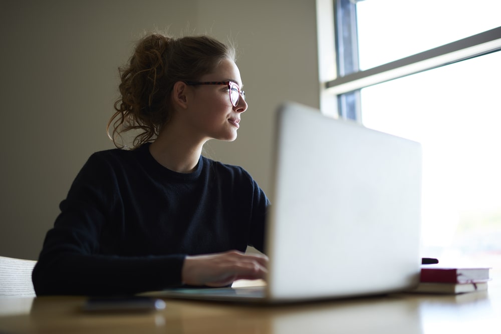 mulher com notebook pensativa para representar texto sobre como se manter atualizado no mercado de trabalho