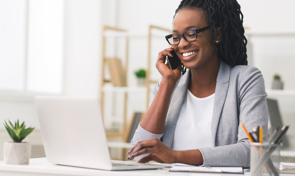 mulher sorrindo no telefone para ilustrar texto sobre motivação no trabalho