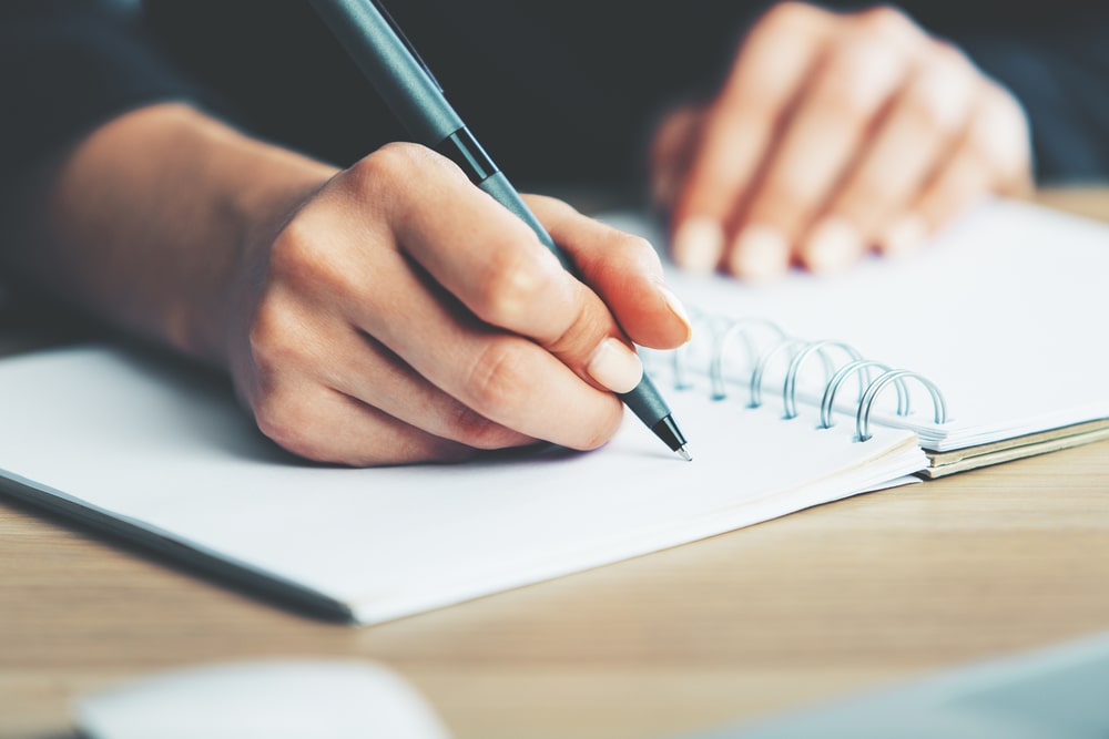 mão em destaque com caneta em um caderno para simular anotações do plano de desenvolvimento profissional