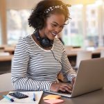 mulher sorrindo digitando no notebook para ilustrar texto sobre novos cursos de pós-graduação