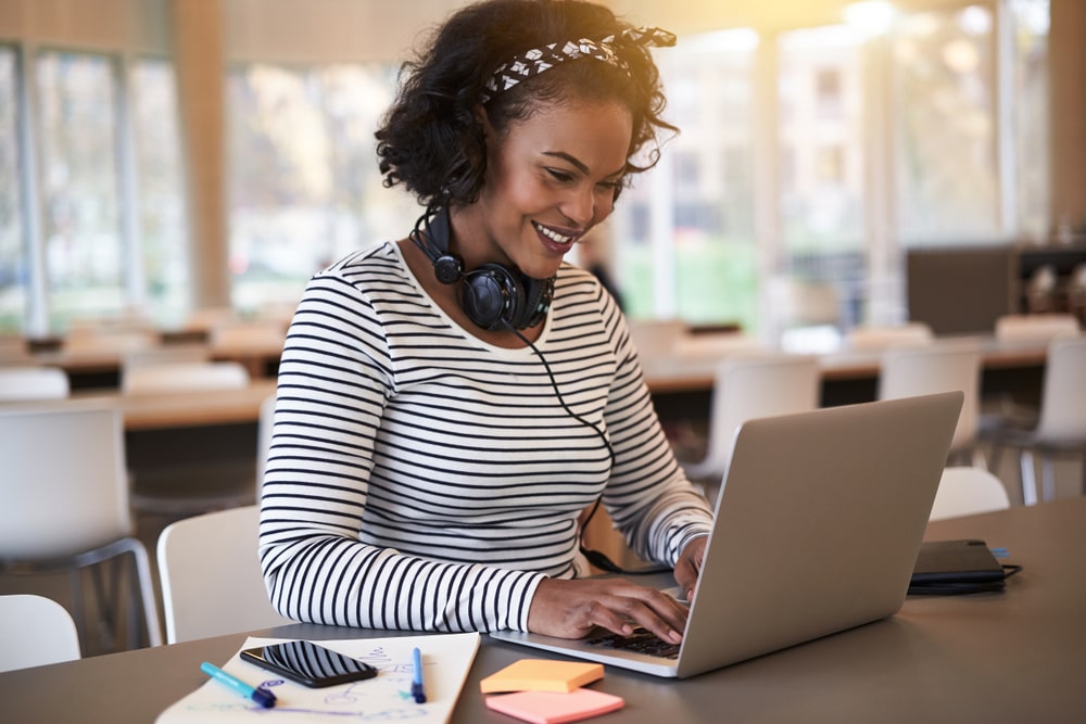 mulher sorrindo digitando no notebook para ilustrar texto sobre novos cursos de pós-graduação