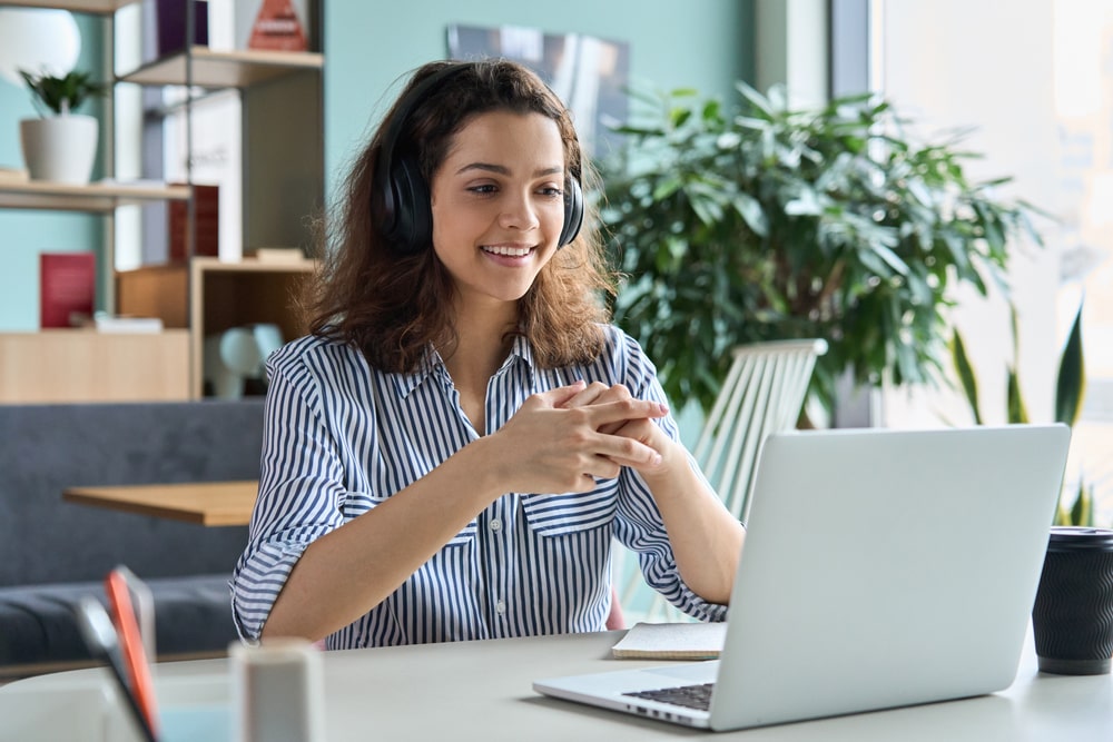 mulher com fone de ouvido na frente do notebook para ilustrar texto sobre tutor online na pós-graduação EAD