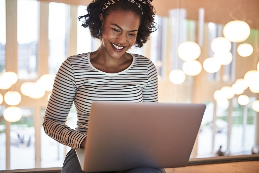 mulher sorrindo e digitando no notebook para ilustrar texto sobre certificado digital