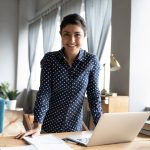 mulher de pé na mesa com notebook para ilustrar texto sobre espírito empreendedor