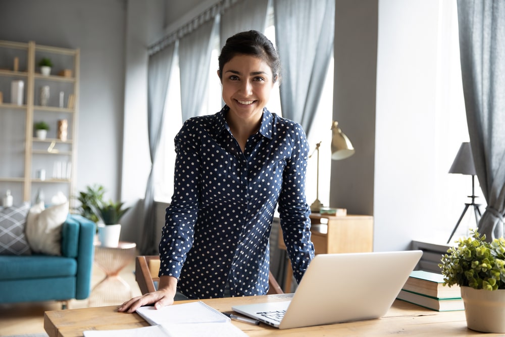 mulher de pé na mesa com notebook para ilustrar texto sobre espírito empreendedor