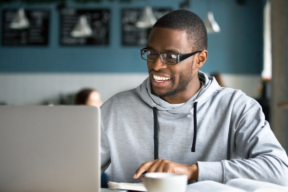 homem sorrindo olhando para o notebook para ilustrar texto sobre por que é importante estudar