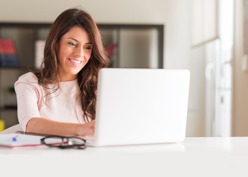 mulher olhando para o notebook com expressão feliz para ilustrar texto sobre o ambiente virtual de aprendizagem da pós-graduação