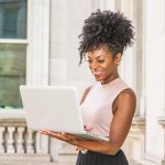 mulher sorrindo com notebook na mão para ilustrar texto sobre mentalidade empreendedora