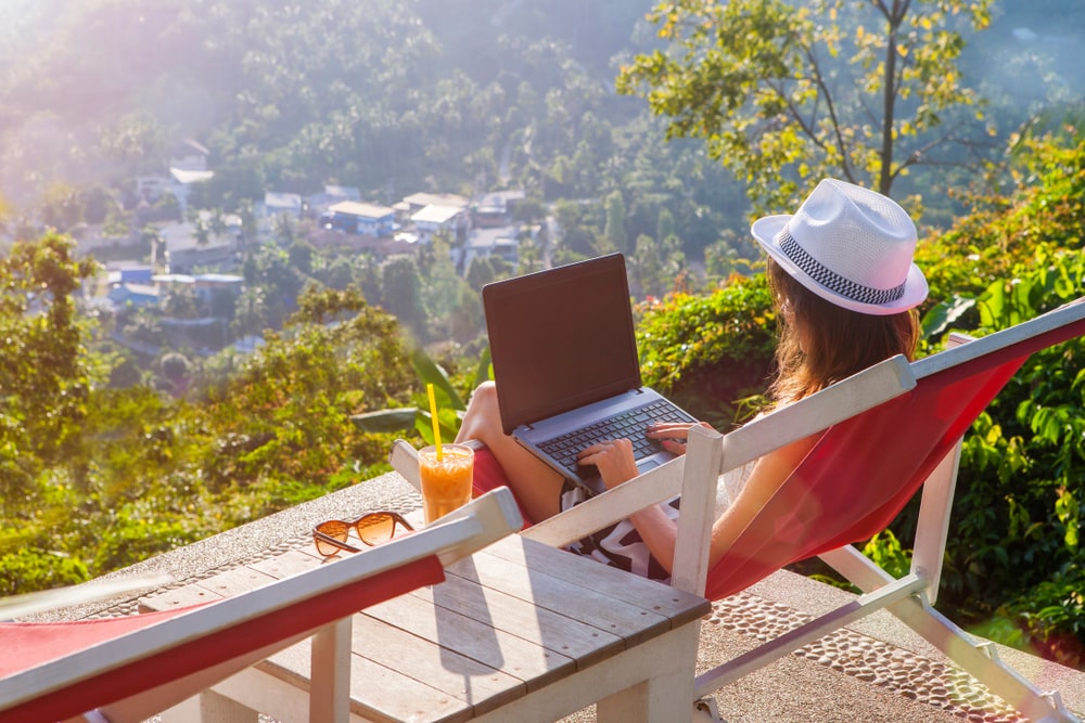 mulher com notebook e paisagem de fundo para ilustrar texto sobre como ser nômade digital