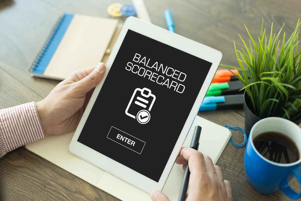 pessoa segurando um tablet com os termos Balanced Scorecard