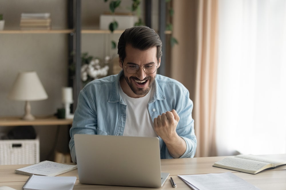 homem comemorando em ambiente de home office para ilustrar texto sobre pós-graduação