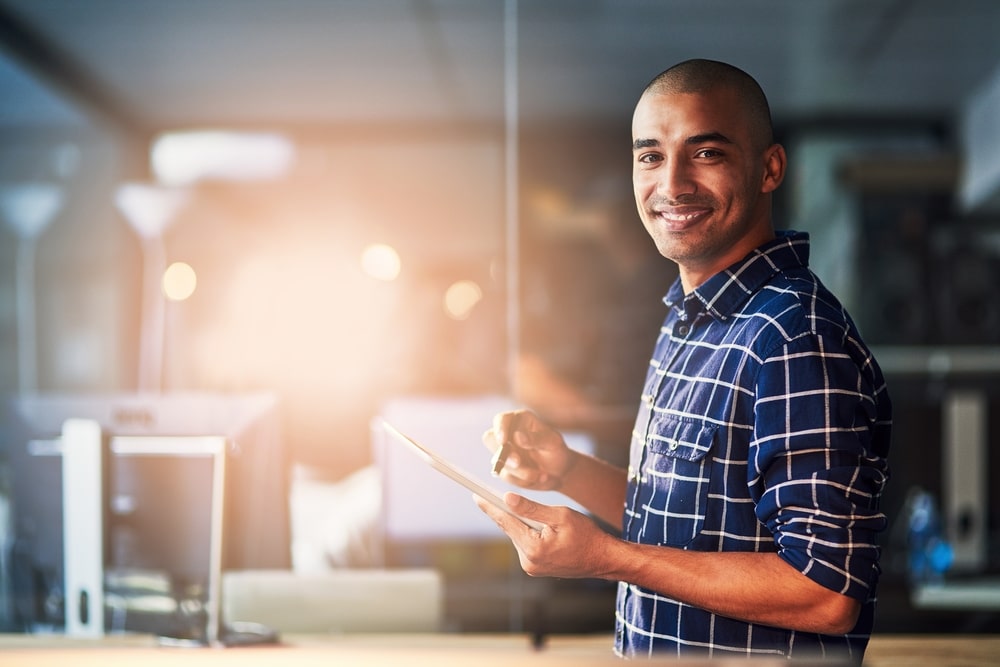 homem sorrindo em ambiente profissional para ilustrar texto sobre carreira e mercado de trabalho