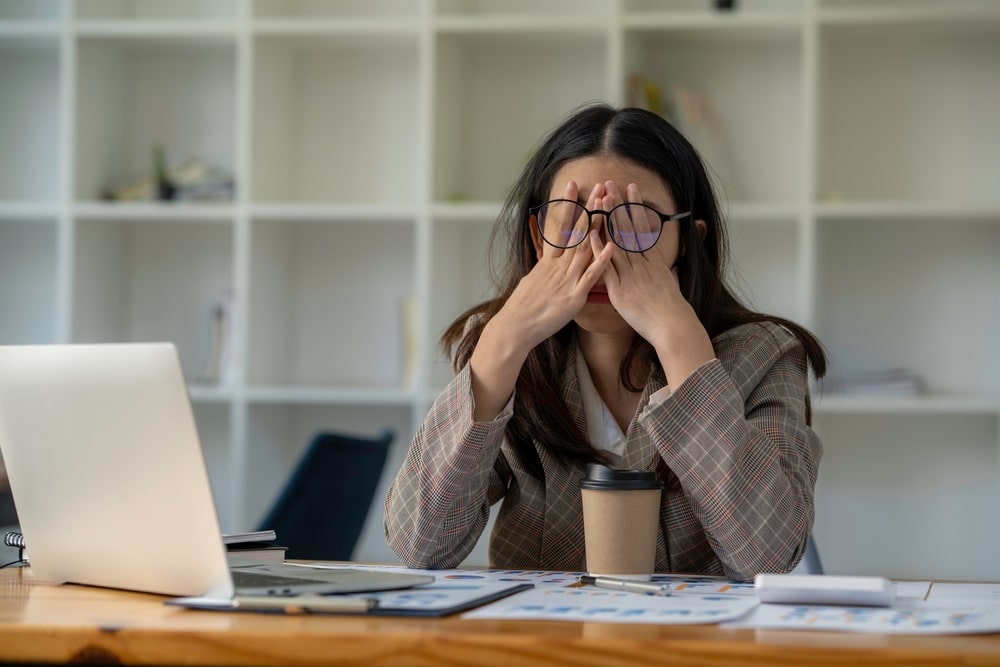 mulher com a mão no rosto para ilustrar texto sobre jornada de trabalho excessiva