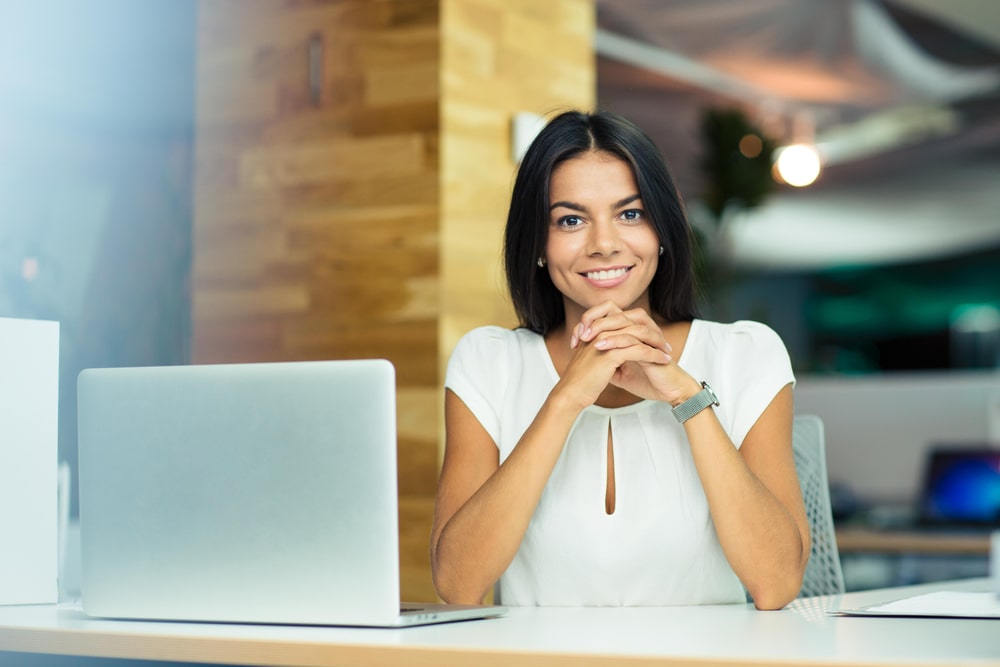 mulher sorrindo com notebook para ilustrar texto sobre nível de senioridade