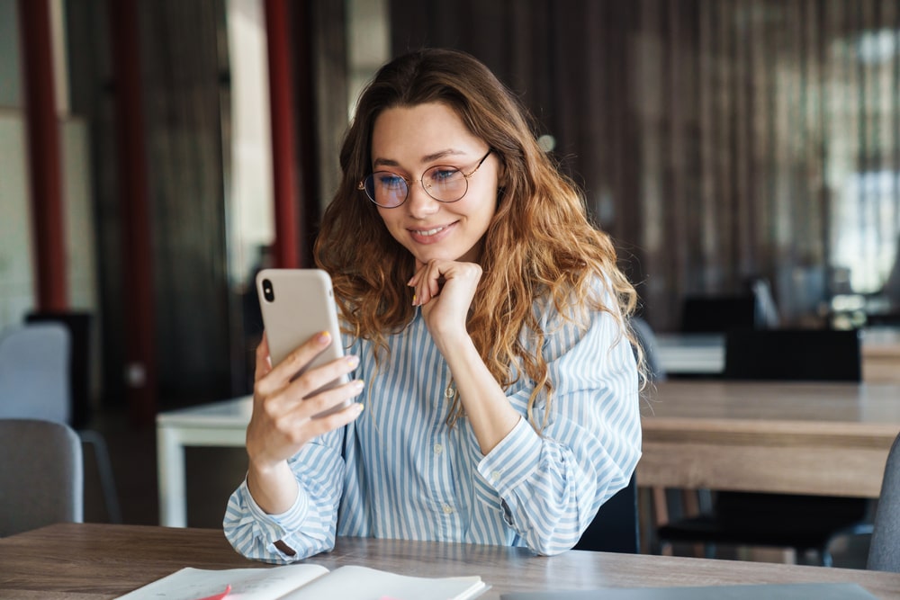 mulher com celular na mão para ilustrar texto sobre como fazer currículo pelo celular em PDF