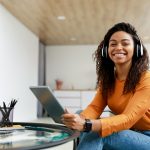 mulher sorrindo com fone para ilustrar texto sobre como ter um dia produtivo nos estudos