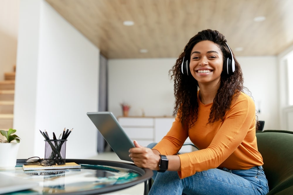 mulher sorrindo com fone para ilustrar texto sobre como ter um dia produtivo nos estudos