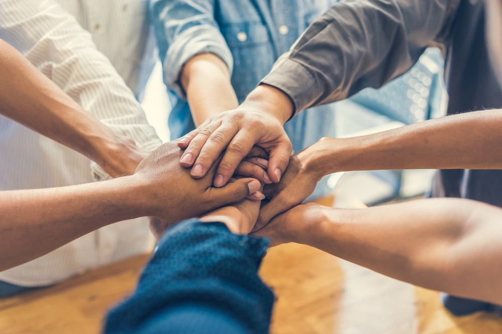 mãos juntas para representar texto sobre saber trabalhar em equipe