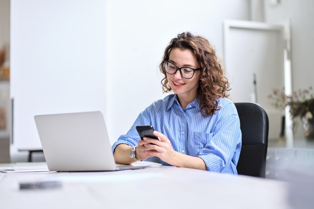 mulher com celular na mão para ilustrar texto sobre como pesquisar empresas no LinkedIn