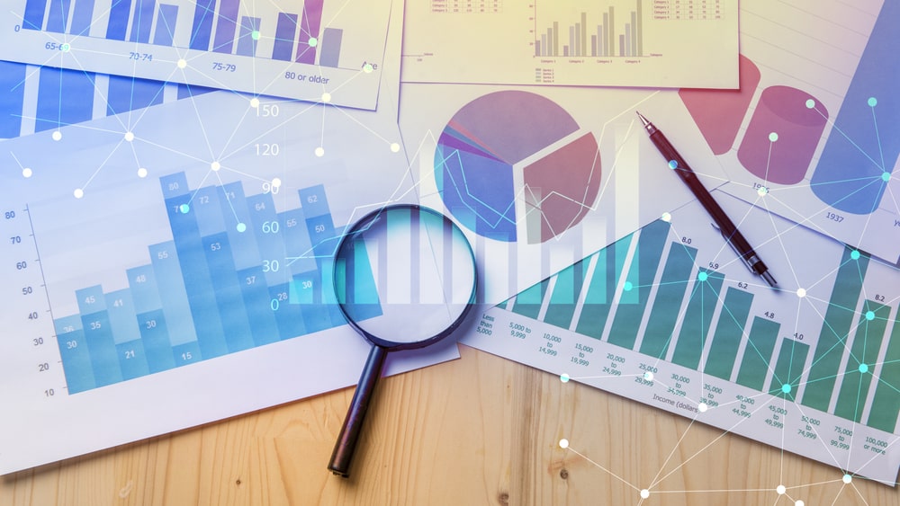 lupa e gráficos para ilustrar texto sobre qual a importância da pesquisa de mercado