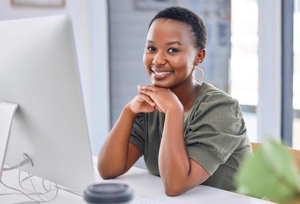 mulher sorrindo no trabalho para ilustrar texto sobre ser você mesmo na carreira