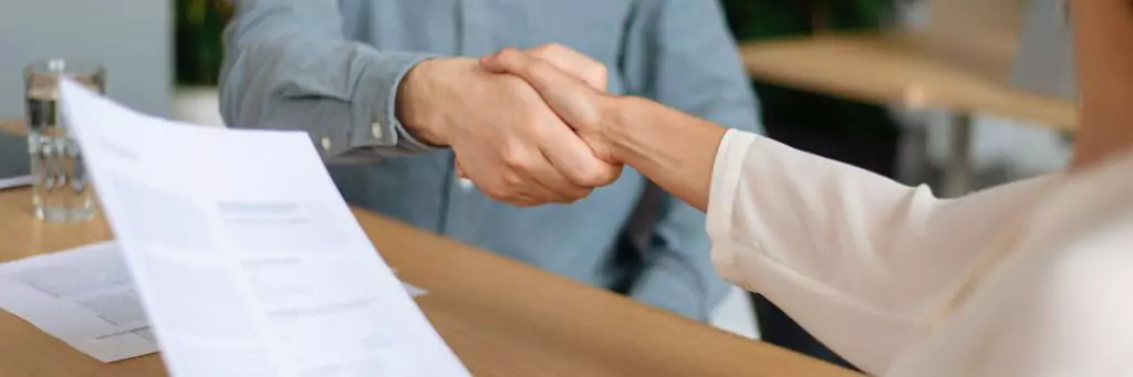 pessoa apertando a mão de outra em entrevista de emprego