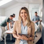 Mulher em um escritório sorri para a foto. Importância do líder no trabalho em equipe